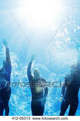 Stock Image - Triathletes in wetsuits underwater. Fotosearch