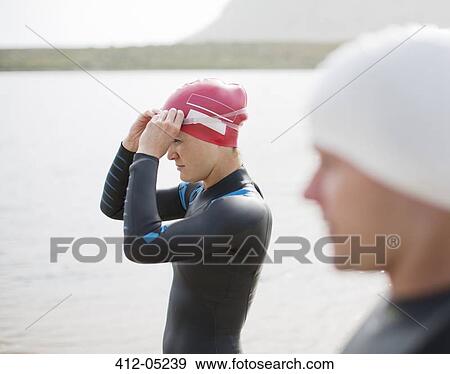 Triathletes pulling on goggles on beach View Large Photo Image Stock Photo - Triathletes pulling on goggles on beach. Fotosearch