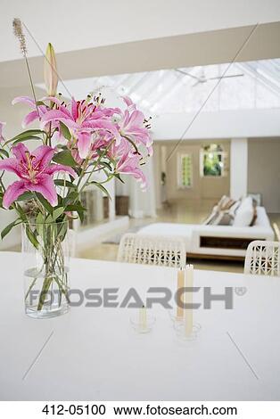 Stock Image - Candles and bouquet of flowers on dining table. Fotosearch
