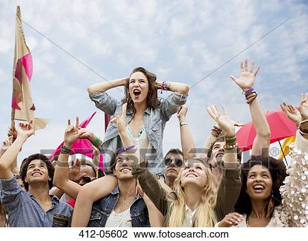 Stock Image - Cheering woman on man's shoulders at music festival. Fotosearch