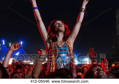Stock Photograph - Cheering woman on man's shoulders at music festival. Fotosearch