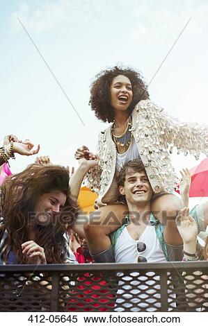 Cheering woman on man's shoulders at music festival View Large Photo Image Stock Photography - Cheering woman on man's shoulders at music festival. Fotosearch
