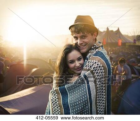 Couple wrapped in a blanket outside tents at music festival View Large Photo Image Stock Photo - Couple wrapped in a blanket outside tents at music festival. Fotosearch