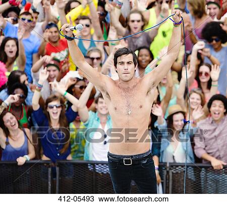 Fans cheering behind performer on stage at music festival View Large Photo Image Stock Image - Fans cheering behind performer on stage at music festival. Fotosearch