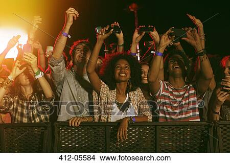 Picture - Fans with camera phones cheering at music festival. Fotosearch