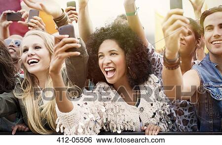 Stock Photograph - Fans with camera phones cheering at music festival. Fotosearch