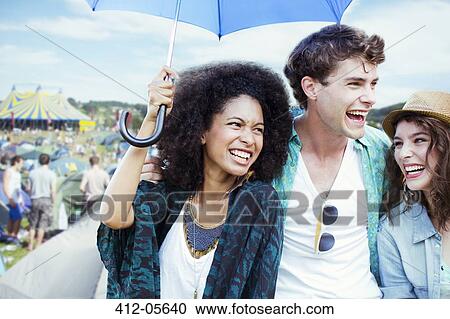 Friends with umbrella at music festival View Large Photo Image Stock Image - Friends with umbrella at music festival. Fotosearch