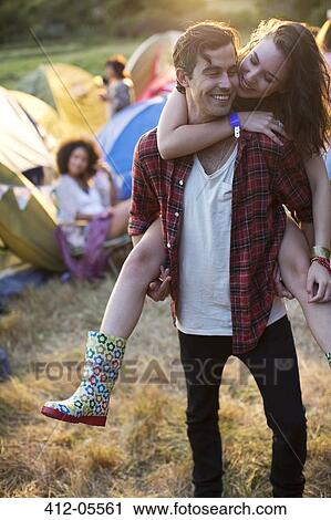 Man piggybacking woman outside tents at music festival View Large Photo Image Stock Image - Man piggybacking woman outside tents at music festival. Fotosearch