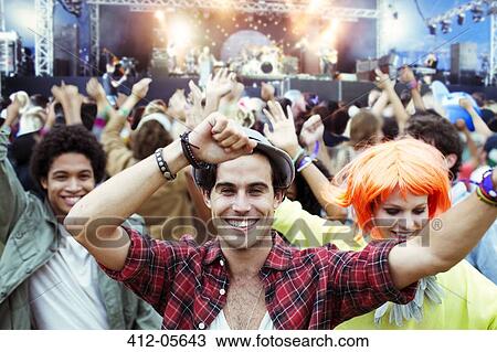 Stock Image - Portrait of fans dancing and cheering at music festival. Fotosearch