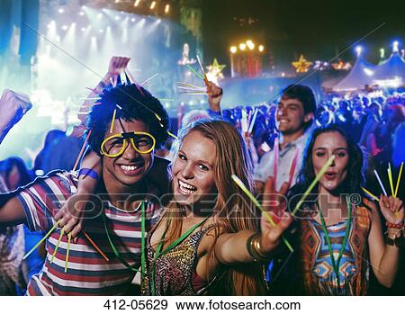 Stock Photo - Portrait of friends with glow sticks at music festival. Fotosearch