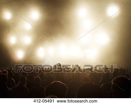 Silhouetted crowd watching illuminated stage at music festival View Large Photo Image Stock Image - Silhouetted crowd watching illuminated stage at music festival. Fotosearch