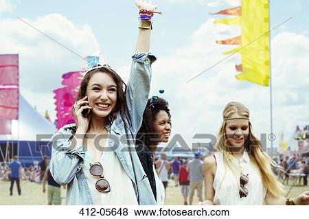 Stock Photo - Woman talking on cell phone at music festival. Fotosearch