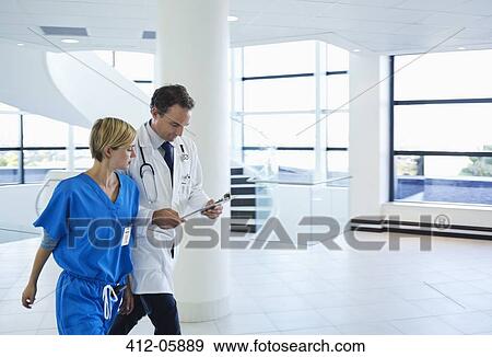 Doctor and nurse talking in hospital hallway View Large Photo Image Stock Photo - Doctor and nurse talking in hospital hallway. Fotosearch