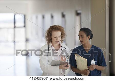 Doctor and nurse talking in hospital hallway View Large Photo Image Stock Photo - Doctor and nurse talking in hospital hallway. Fotosearch
