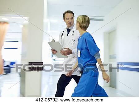 Doctor and nurse walking in hospital hallway View Large Photo Image Stock Image - Doctor and nurse walking in hospital hallway. Fotosearch