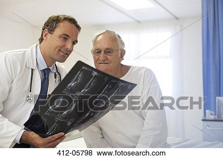 Doctor and patient examining x-rays in hospital room View Large Photo Image Stock Photo - Doctor and patient examining x-rays in hospital room. Fotosearch
