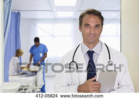 Doctor carrying tablet computer in hospital View Large Photo Image Picture - Doctor carrying tablet computer in hospital. Fotosearch
