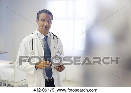 Doctor reading clipboard in hospital room View Large Photo Image Stock Photo - Doctor reading clipboard in hospital room. Fotosearch