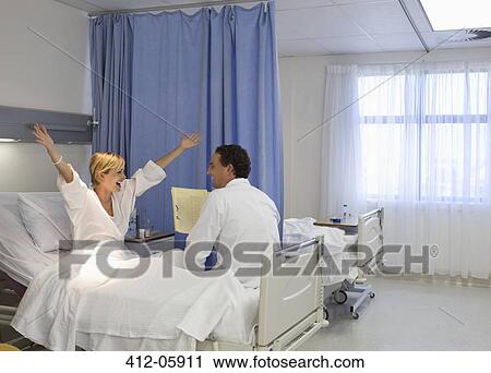 Doctor talking to cheering patient in hospital room View Large Photo Image Stock Image - Doctor talking to cheering patient in hospital room. Fotosearch