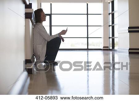 Doctor using cell phone in hospital hallway View Large Photo Image Stock Image - Doctor using cell phone in hospital hallway. Fotosearch