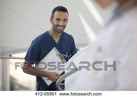 Nurse carrying clipboard in hospital hallway View Large Photo Image Stock Image - Nurse carrying clipboard in hospital hallway. Fotosearch