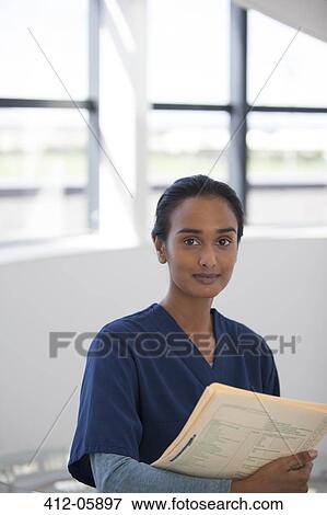 Nurse carrying folder in hospital hallway View Large Photo Image Stock Photo - Nurse carrying folder in hospital hallway. Fotosearch