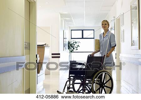 Stock Photograph - Nurse pushing wheelchair in hospital hallway. Fotosearch