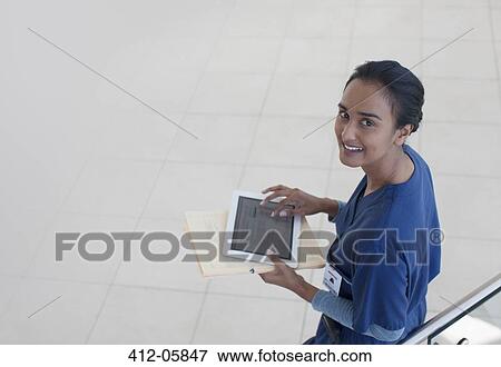 Stock Photo - Nurse using tablet computer in hospital hallway. Fotosearch