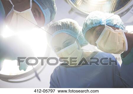 Surgeons bent over patient in operating room View Large Photo Image Stock Photo - Surgeons bent over patient in operating room. Fotosearch