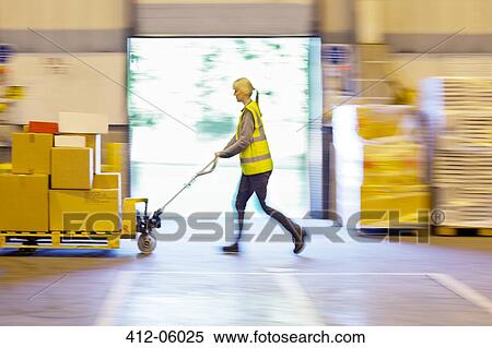 Stock Photography - Blurred view of worker carting boxes in warehouse. Fotosearch