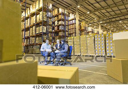 Stock Image - Business people talking in warehouse. Fotosearch