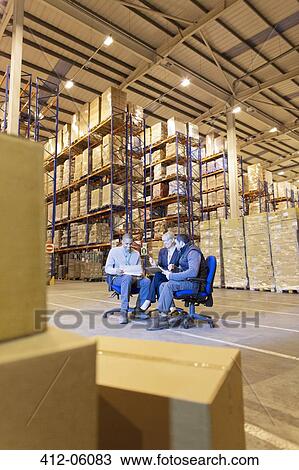 Stock Image - Business people talking in warehouse. Fotosearch