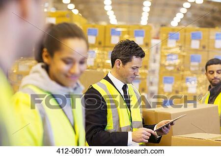 Stock Photo - Businessman and workers in warehouse. Fotosearch