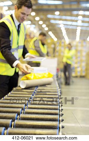 Businessman checking packages on conveyor belt in warehouse View Large Photo Image Stock Image - Businessman checking packages on conveyor belt in warehouse. Fotosearch