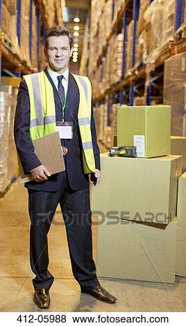 Businessman holding clipboard in warehouse View Large Photo Image Stock Photo - Businessman holding clipboard in warehouse. Fotosearch