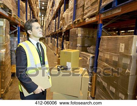 Businessman holding clipboard in warehouse View Large Photo Image Stock Photograph - Businessman holding clipboard in warehouse. Fotosearch