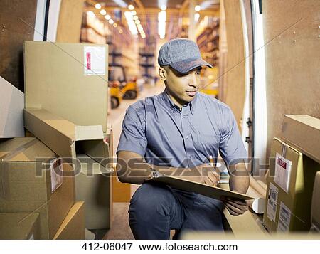 Stock Photo - Delivery boy checking boxes in van. Fotosearch