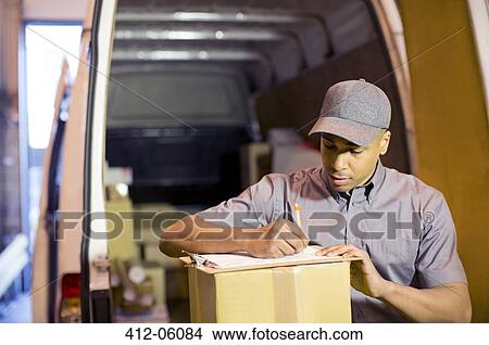 Delivery boy writing on clipboard in van View Large Photo Image Picture - Delivery boy writing on clipboard in van. Fotosearch