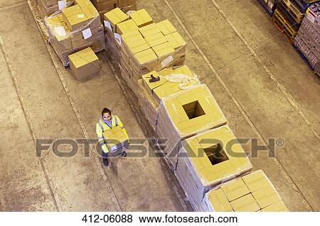 Worker carrying box in warehouse View Large Photo Image Stock Photo - Worker carrying box in warehouse. Fotosearch