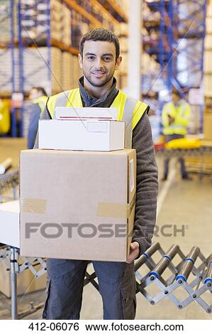 Stock Photograph - Worker carrying boxes in warehouse. Fotosearch