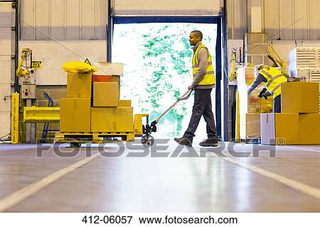 Worker carting boxes in warehouse View Large Photo Image Stock Photo - Worker carting boxes in warehouse. Fotosearch