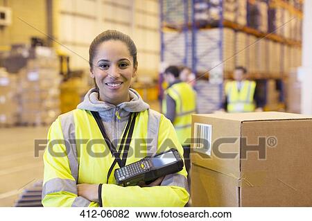 Stock Image - Worker holding scanner in warehouse. Fotosearch
