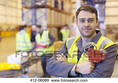 Stock Photo - Worker holding tape dispenser in warehouse. Fotosearch