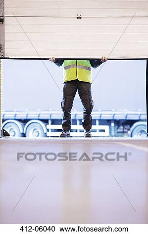 Worker lifting door in warehouse View Large Photo Image Stock Image - Worker lifting door in warehouse. Fotosearch