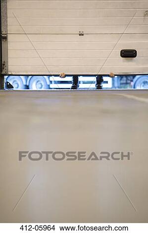 Worker lifting garage door in warehouse View Large Photo Image Picture - Worker lifting garage door in warehouse. Fotosearch