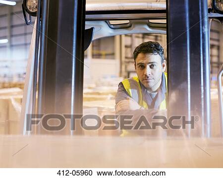 Stock Image - Worker operating forklift in warehouse. Fotosearch