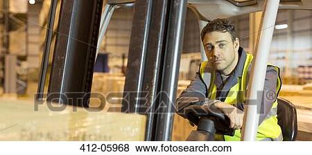 Stock Photo - Worker operating machinery in warehouse. Fotosearch