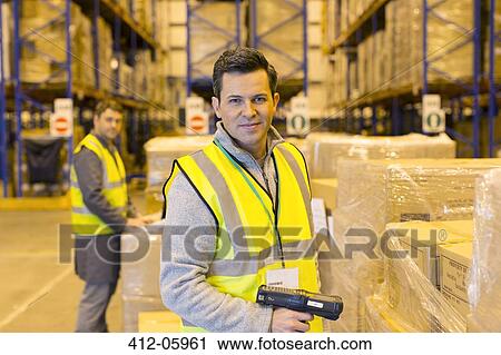 Stock Image - Worker scanning boxes in warehouse. Fotosearch