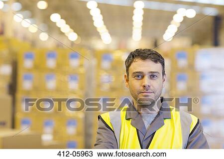 Stock Image - Worker standing in warehouse. Fotosearch