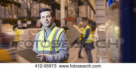 Stock Image - Worker using clipboard in warehouse. Fotosearch